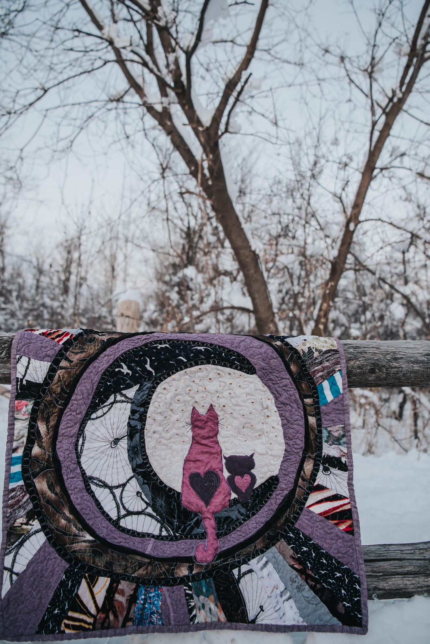 Quilt showing a cat and owl silhouette sitting on the moon made with clothing.