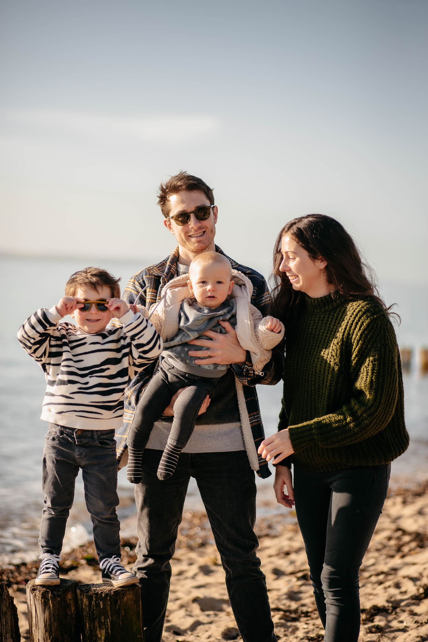 Family enjoying time together on beach with mountains in background during golden hour.