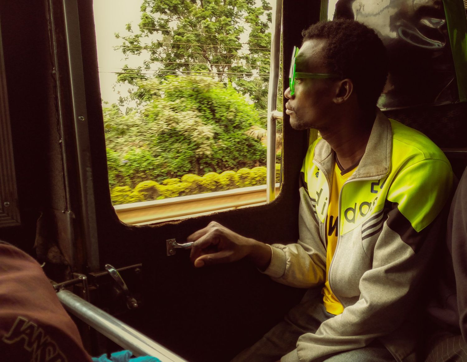 a man watching the nature via a window on a matatu