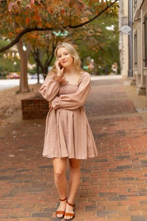 A romantic autumn portrait on brick sidewalk featuring a dusty pink midi dress and brown sandals.