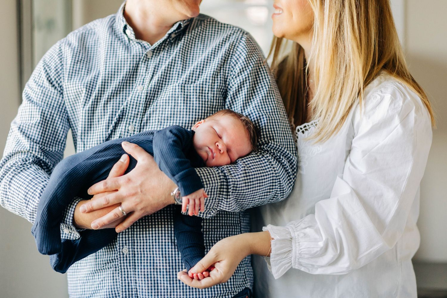A newborn baby boy rests in his parents arms Captured By Grace Photography Traverse City Michigan