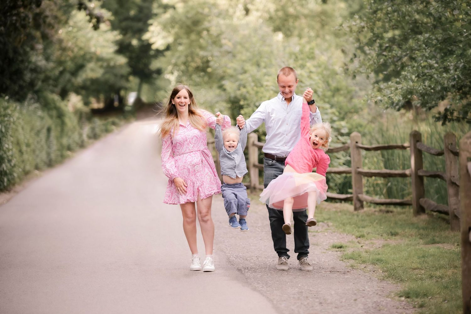 Family walking together on a countryside path wearing pink and casual attire.