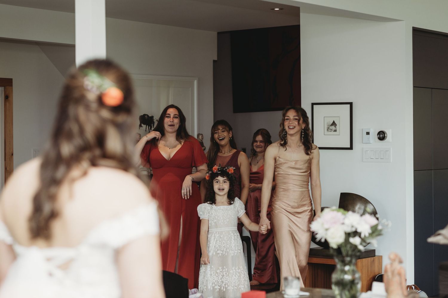 Wedding party gathering in modern interior with bridesmaids in warm-toned dresses.
