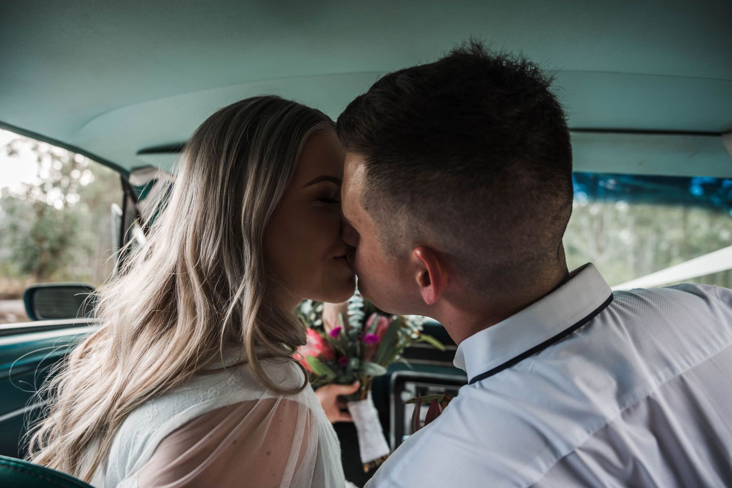 bride and groom kissing in car