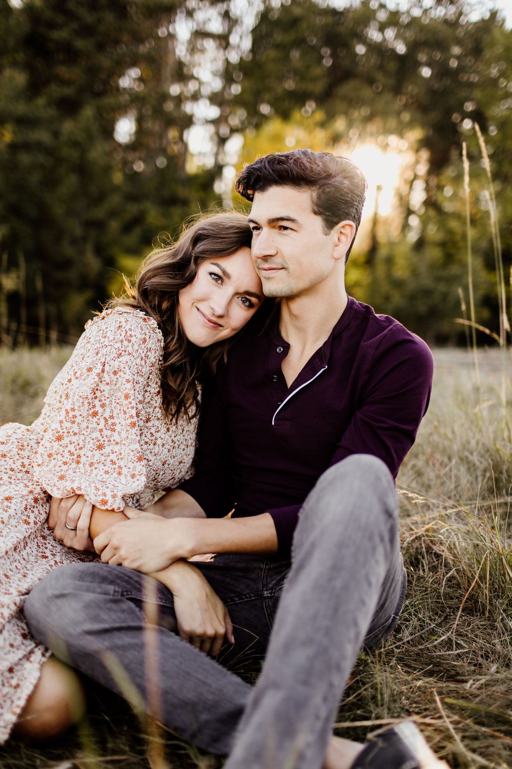 Couple sharing intimate moment while sitting in field during sunset.