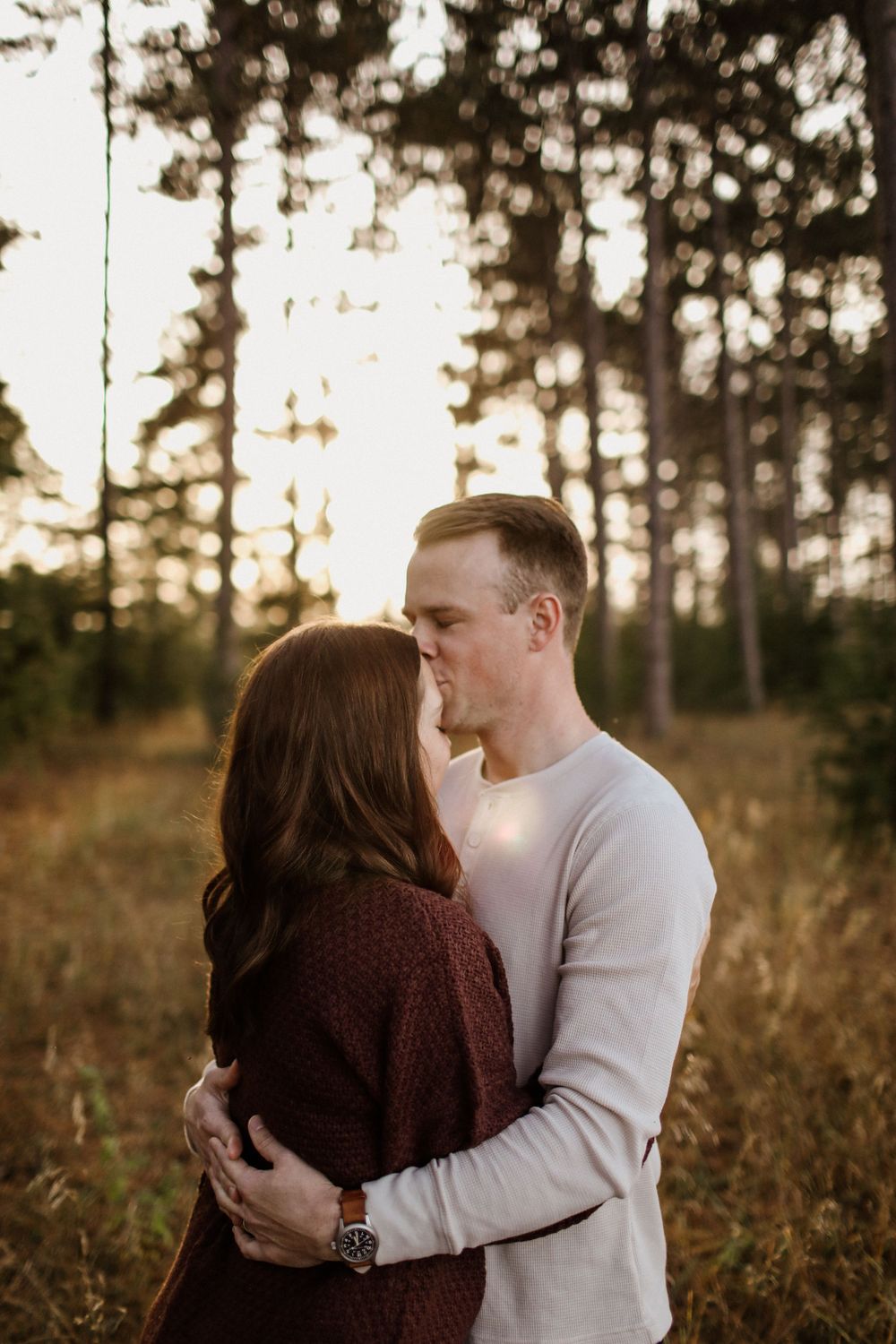 Romantic couple embracing in forest during sunset golden hour.