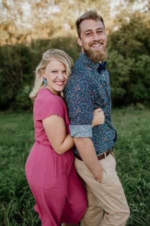 Playful couple embracing and laughing together in an outdoor garden setting during a photo session.