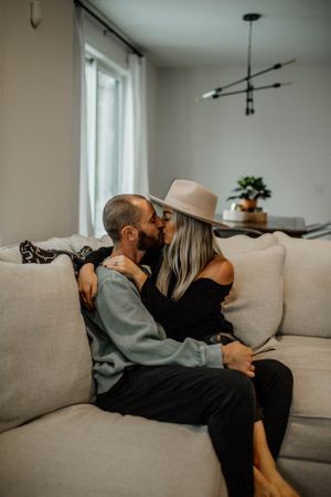 Intimate couple lounging together on a gray couch in a minimalist living room.