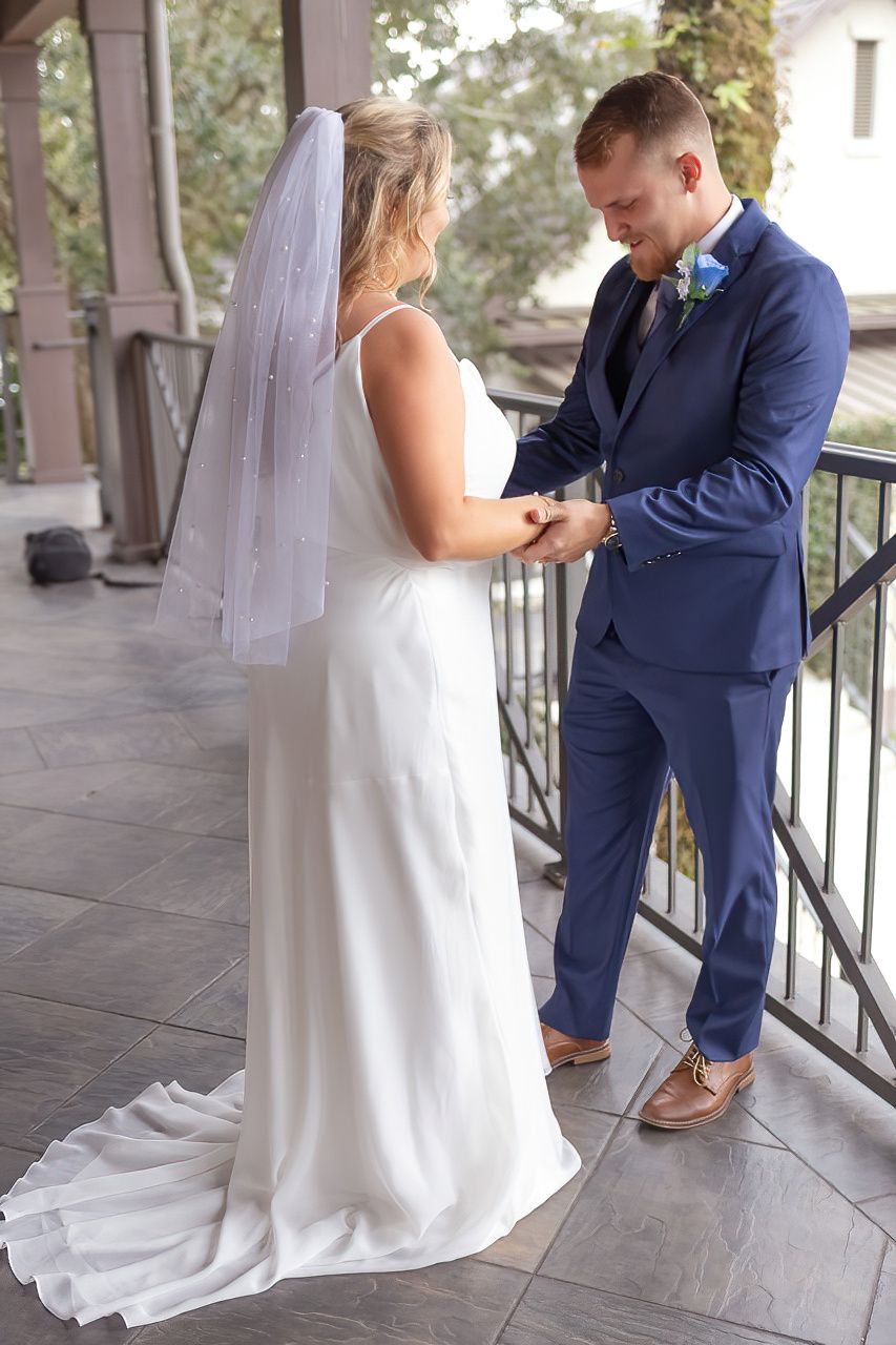 Wedding couple sharing moments on covered porch with white dress and navy suit.
