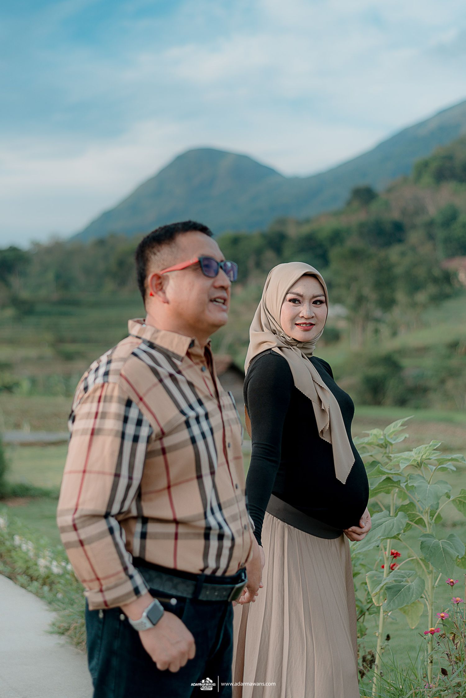 Couple standing together against scenic mountain landscape with traditional attire.