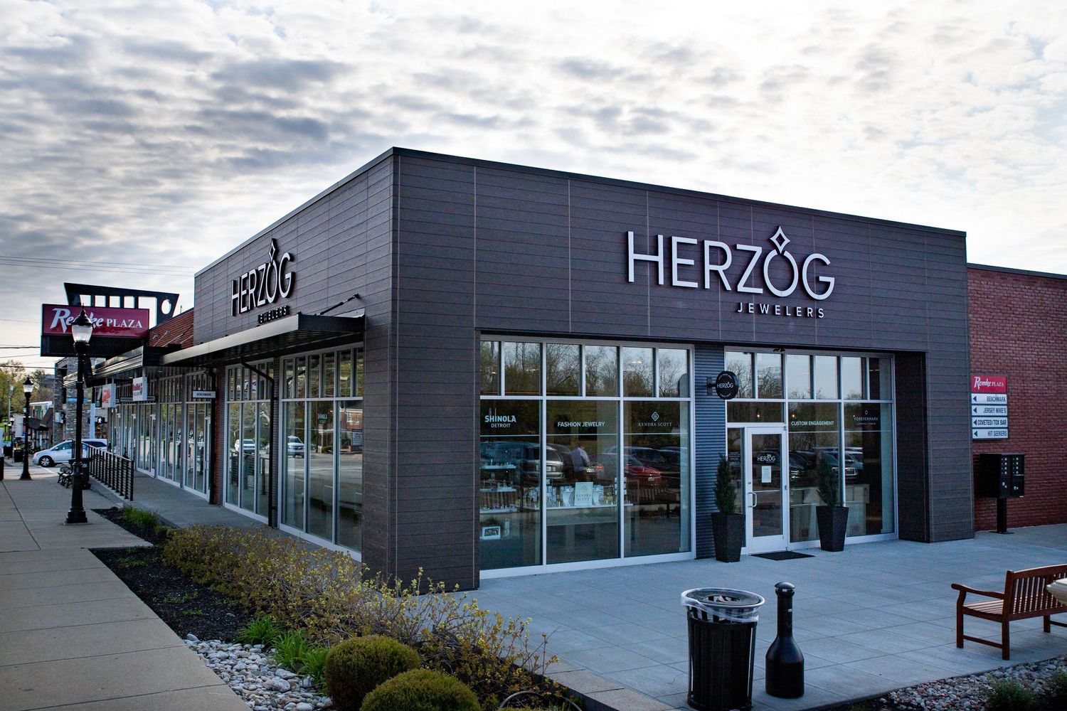 Exterior view of Herzog jewelry store with modern grey facade and signage.