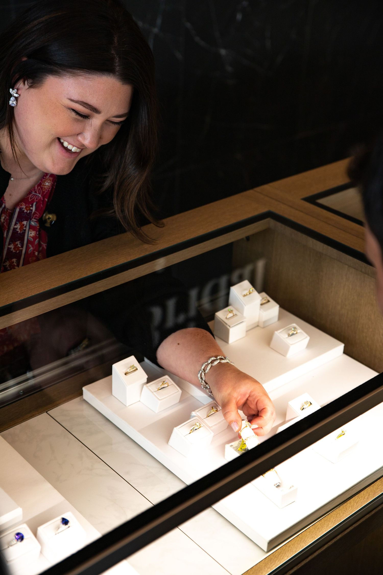 Sales associate smiling while arranging jewelry display case.