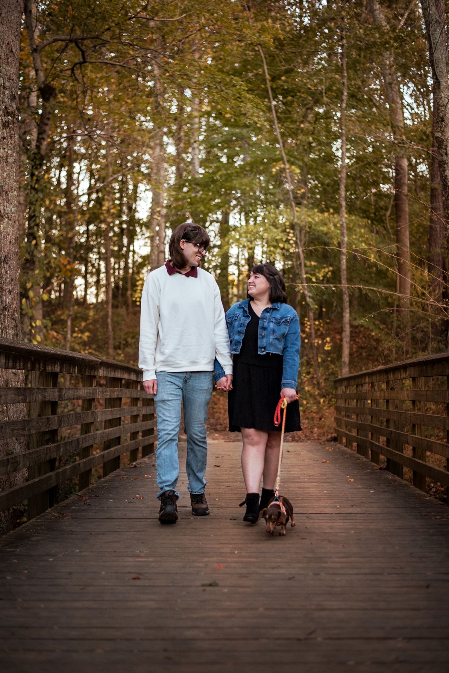 couple walking on a bridge with dachshund