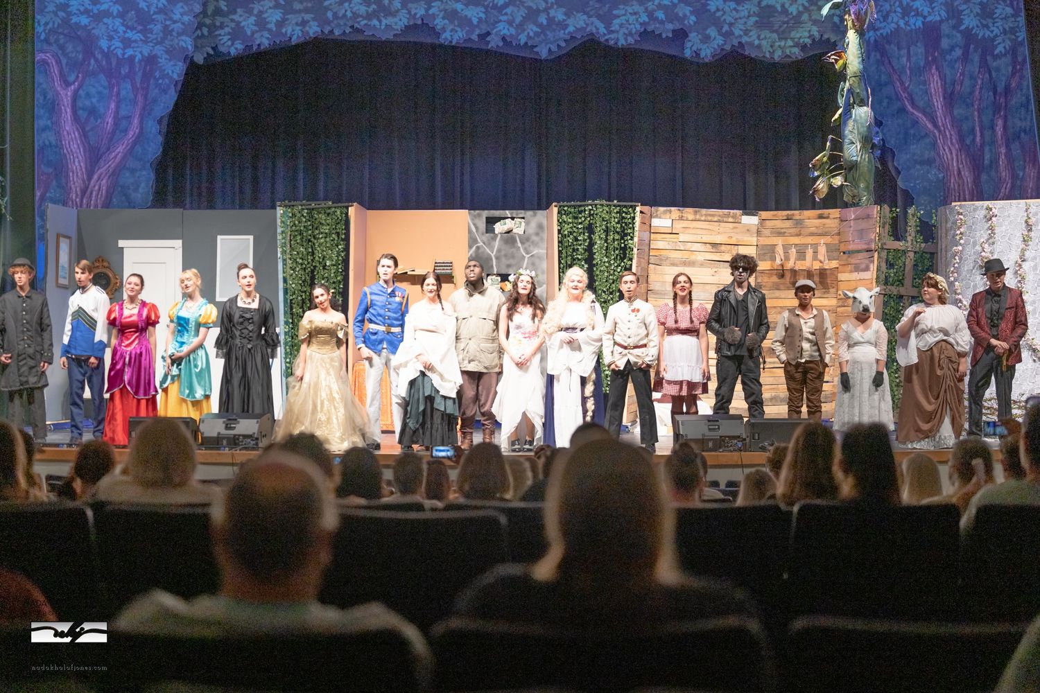 Wide shot of stage performers during theatrical production with blue lighting effects.