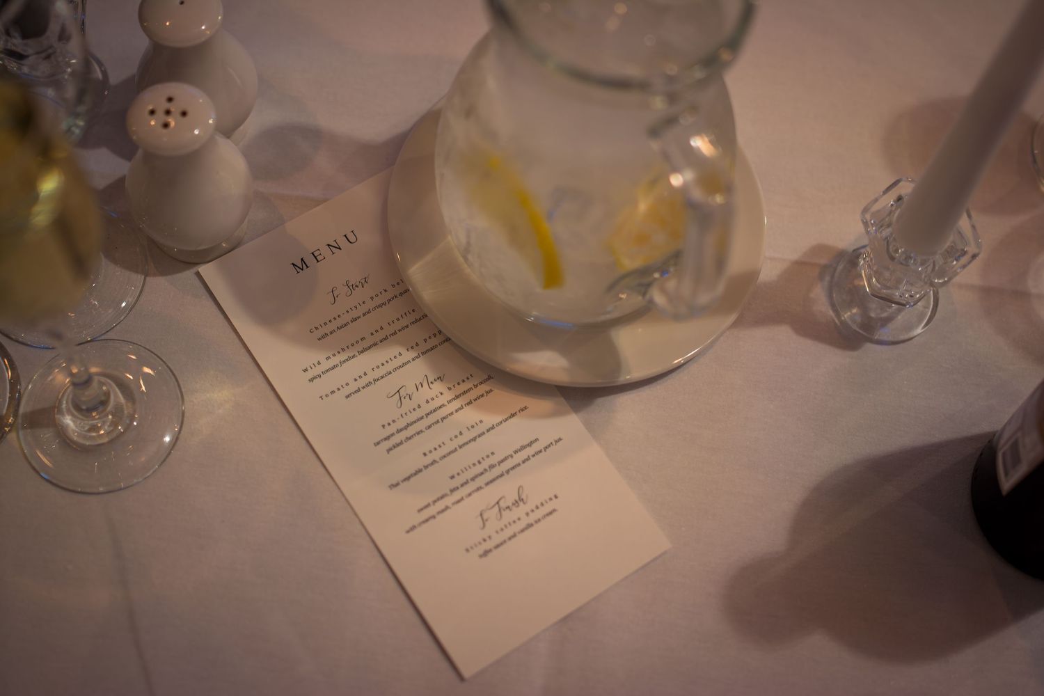 Wedding menu card placed on elegant table setting with glassware and delicate details.