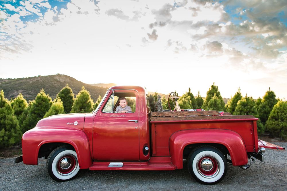 Photo of a little boy in a vintage red truck at Peltzer Pines Christmas Tree Farm in Orange County, CAon