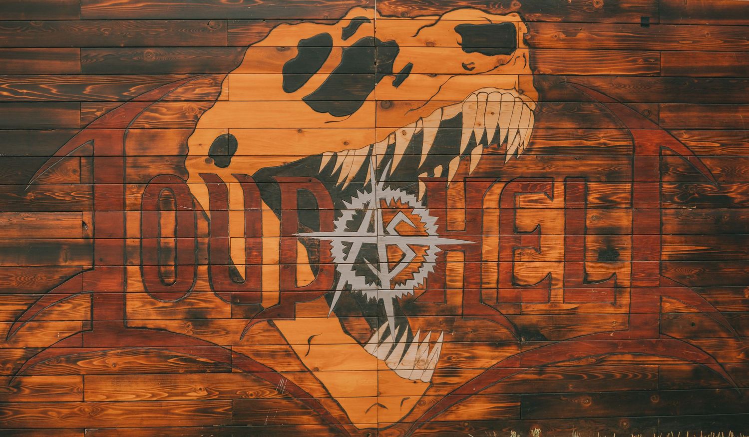 Orange T-Rex skull design with musical notes painted on wooden planks.