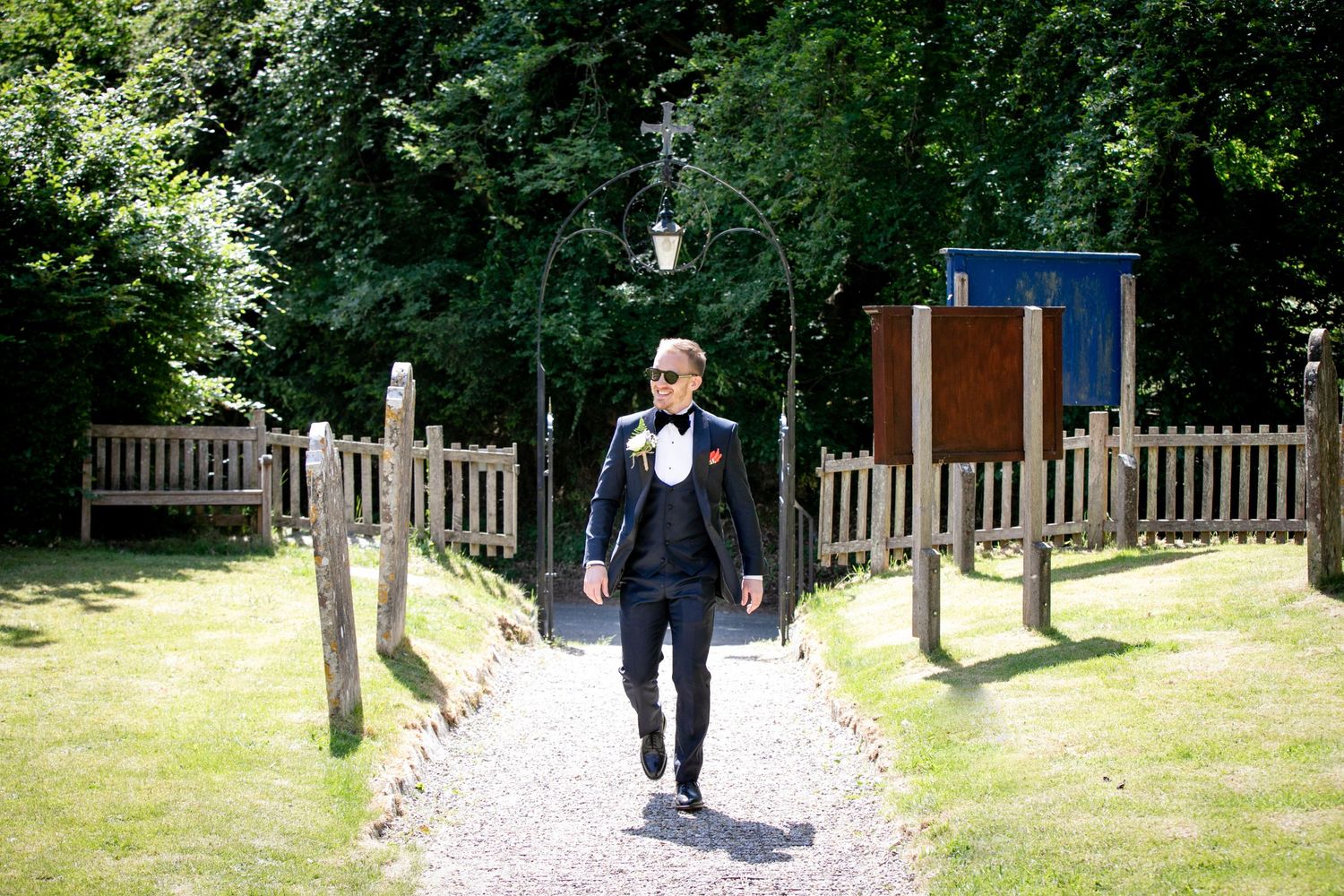 Wedding guests walking along a tree-lined pathway outside a venue.