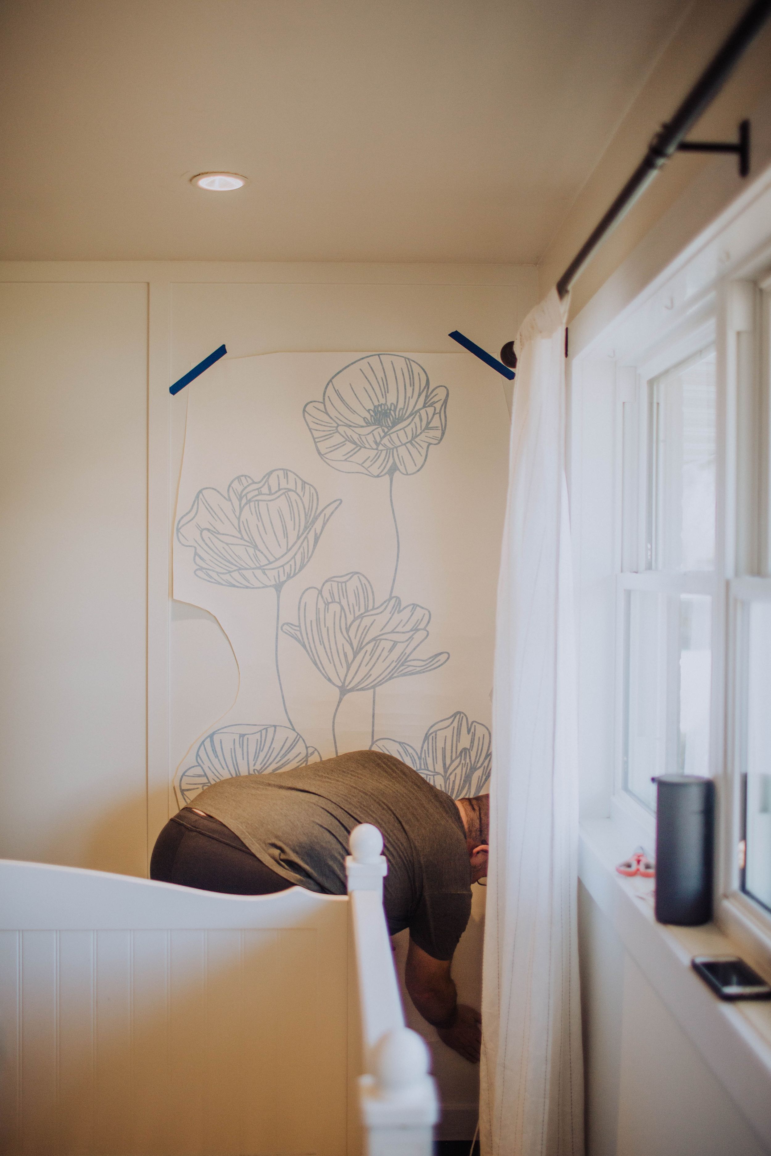 Large floral outline drawings being created on bedroom wall.