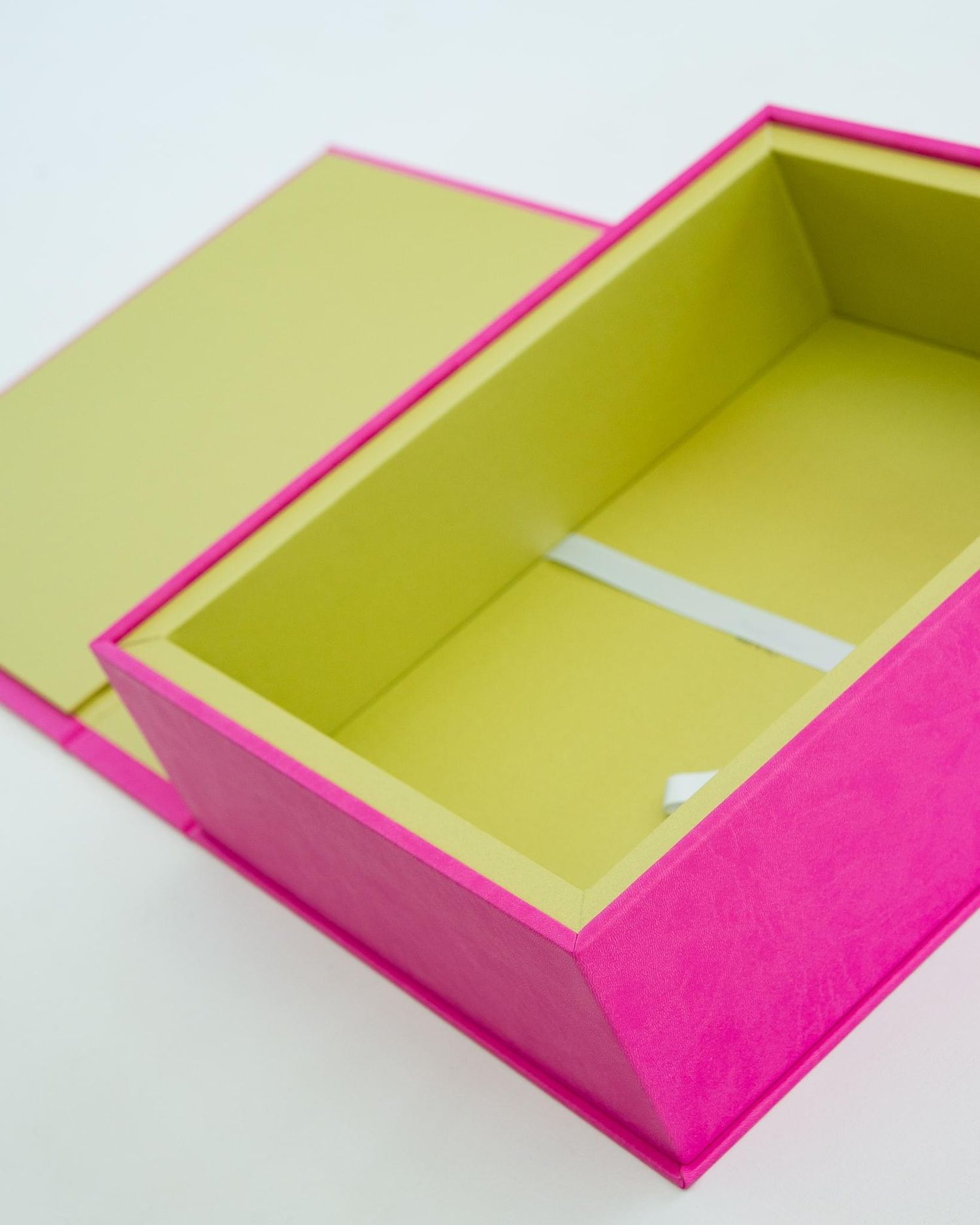 Open pink and yellow gift box with interior divider on white background.