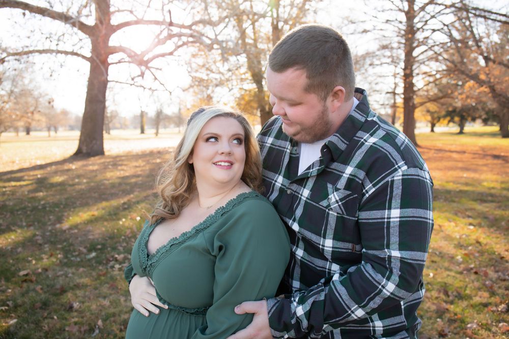 A couple shares a loving moment in an autumn park with golden sunlight.