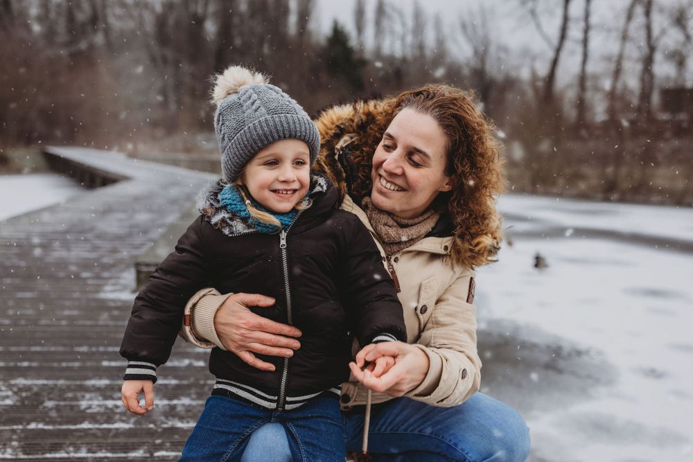 Heartwarming interaction between two people sharing laughter on snowy boardwalk.