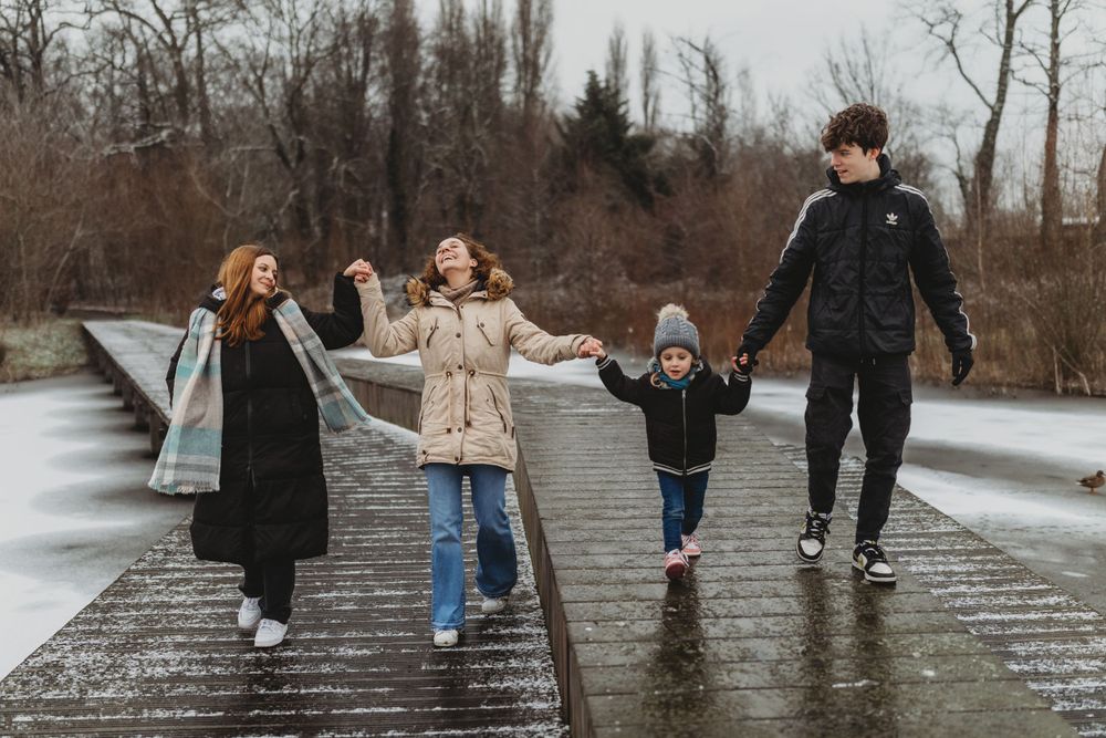 Group enjoying a playful walk together on wooden boardwalk in winter landscape.