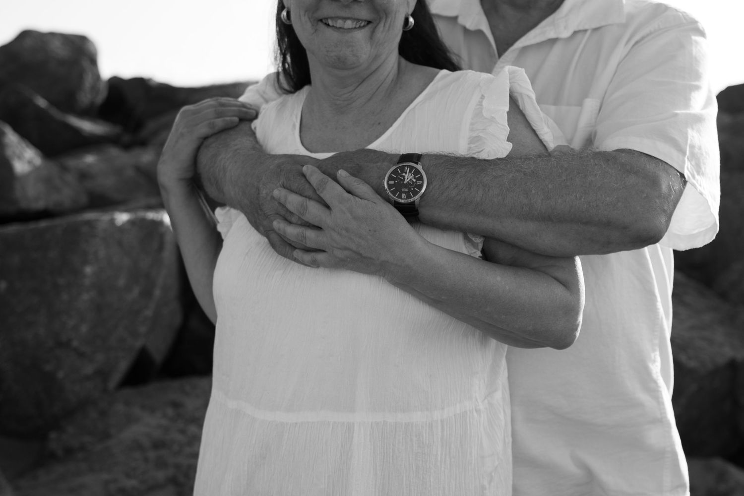 senior couple, on a beach, focus on hands holding and time metaphor with watch on mans wrist.