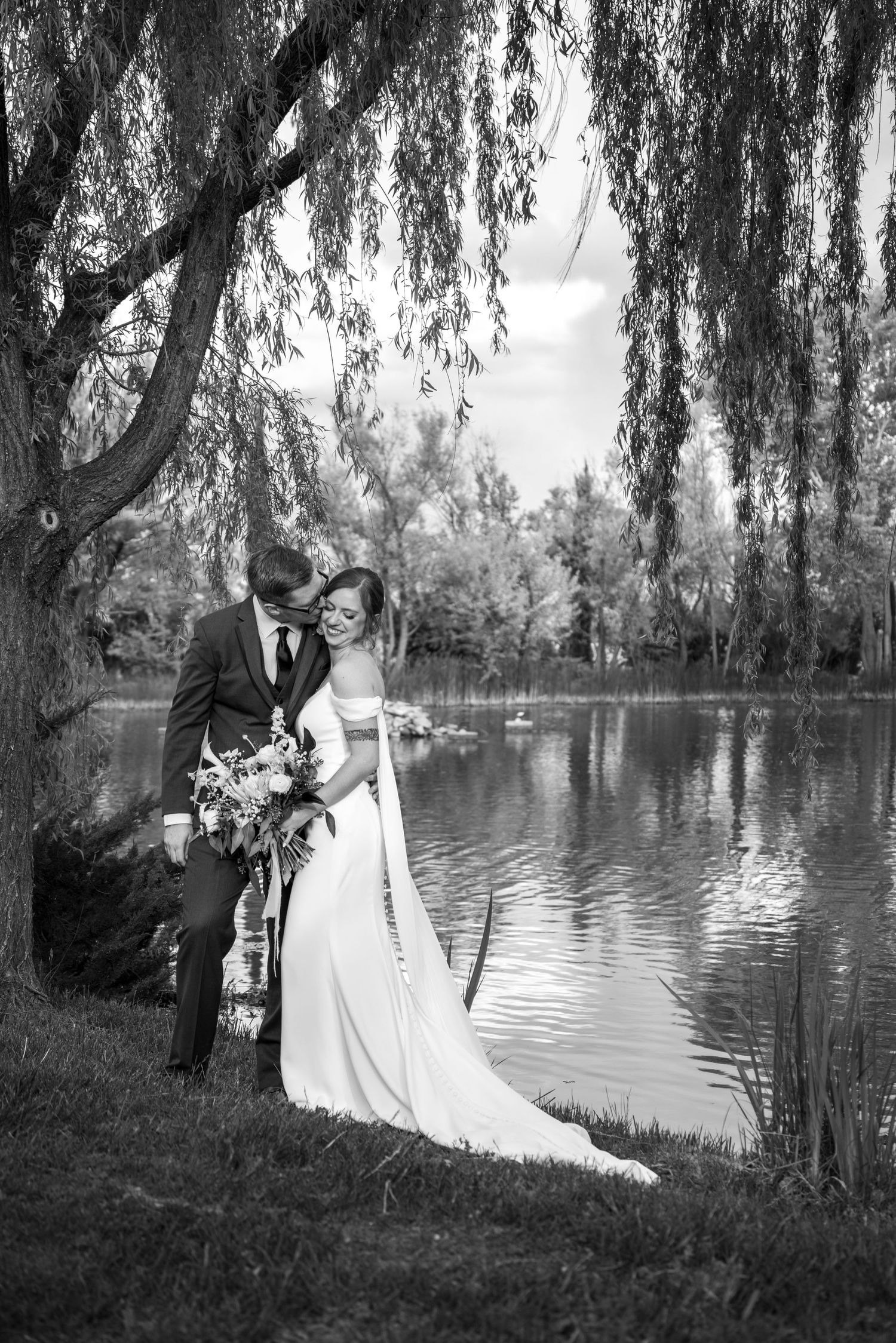 Black and white portrait of a couple under a weeping willow tree by a serene lake. Wedding Photography Sedona