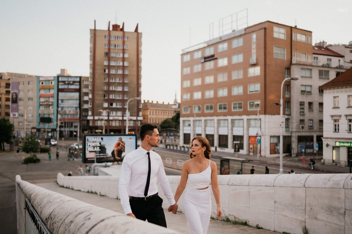 A couple in wedding attire sharing a moment on an urban rooftop surrounded by apartment buildings.