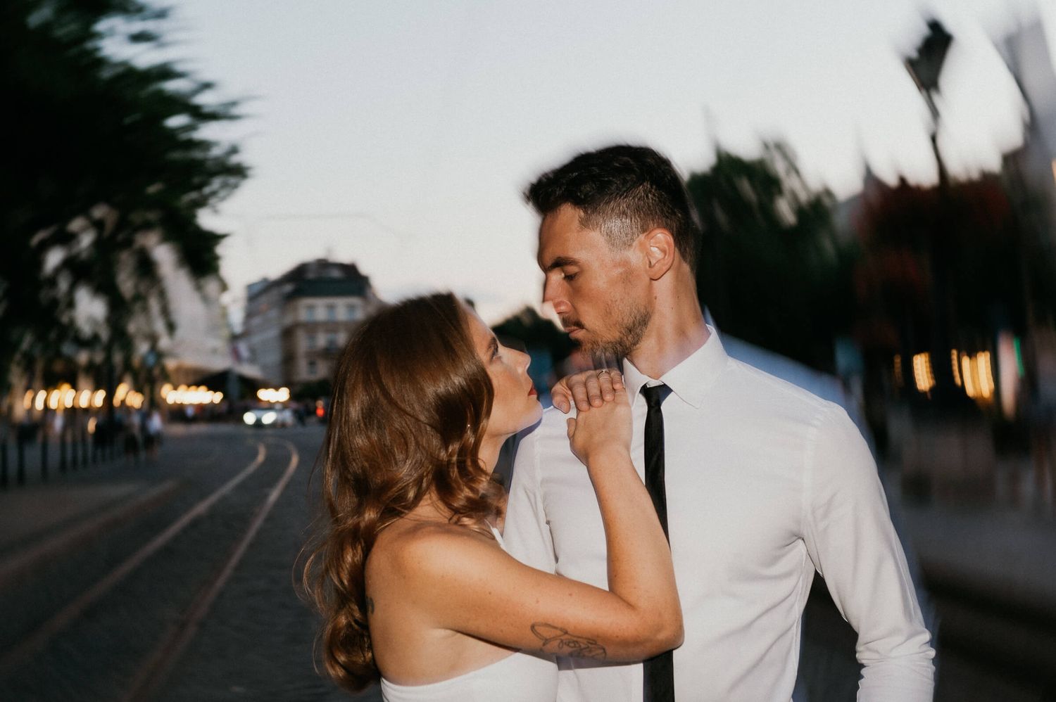 A romantic couple embraces during sunset on an urban street.