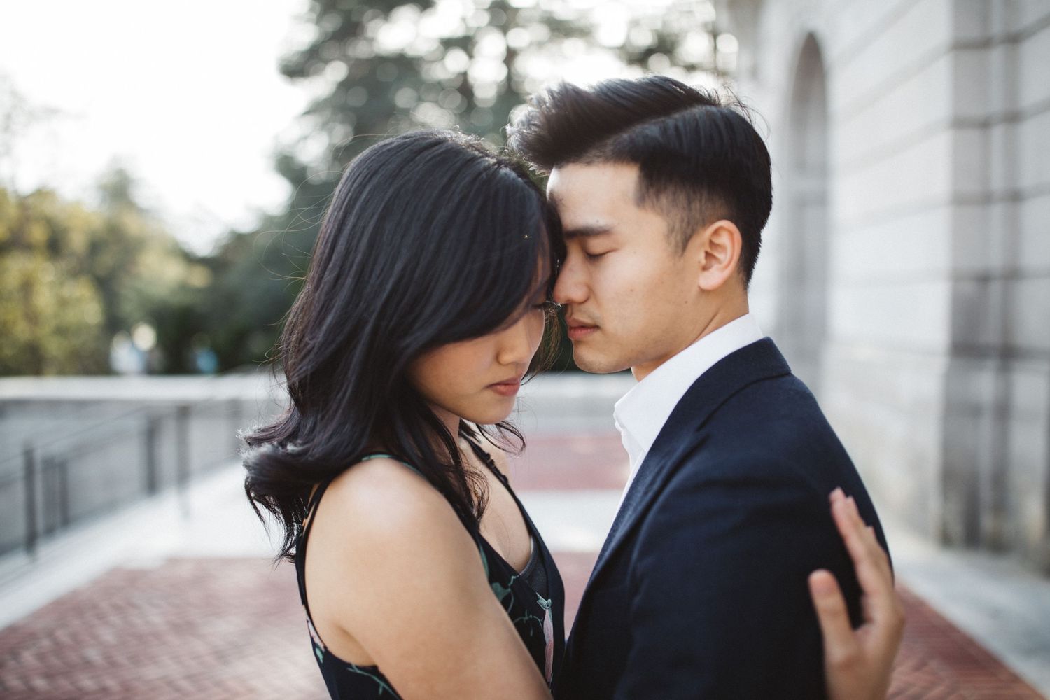 An intimate portrait of a couple in formal attire sharing a close moment outdoors.
