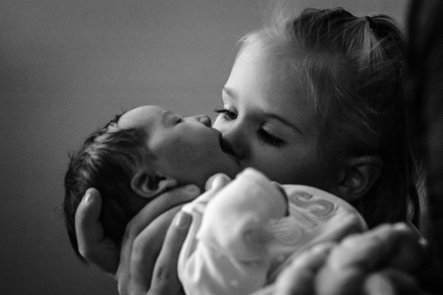 Big sister giving her new baby sister a kiss when she first met the day after she was born in Sioux City, IA.