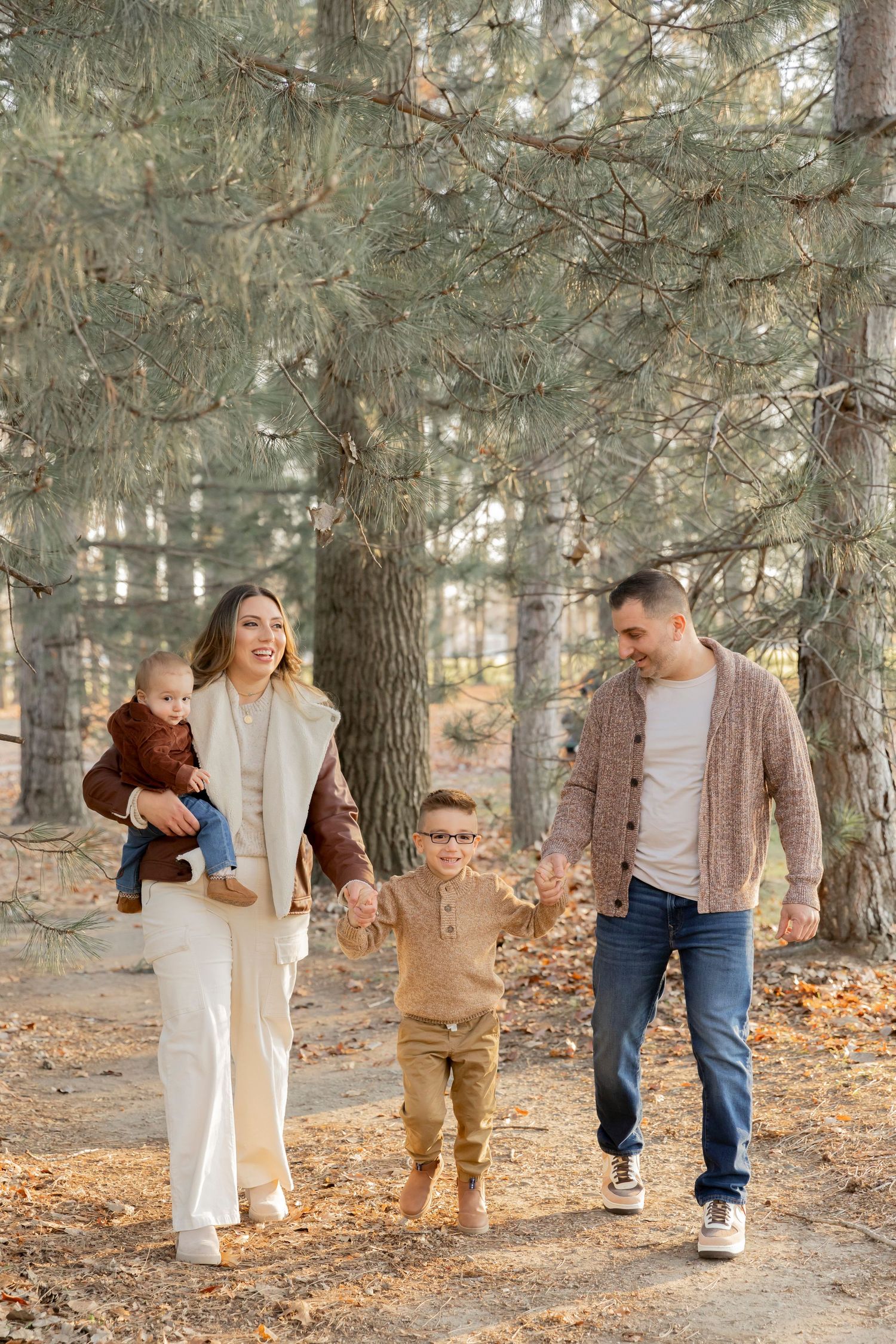 family walking in an evergreen forest and holding hands