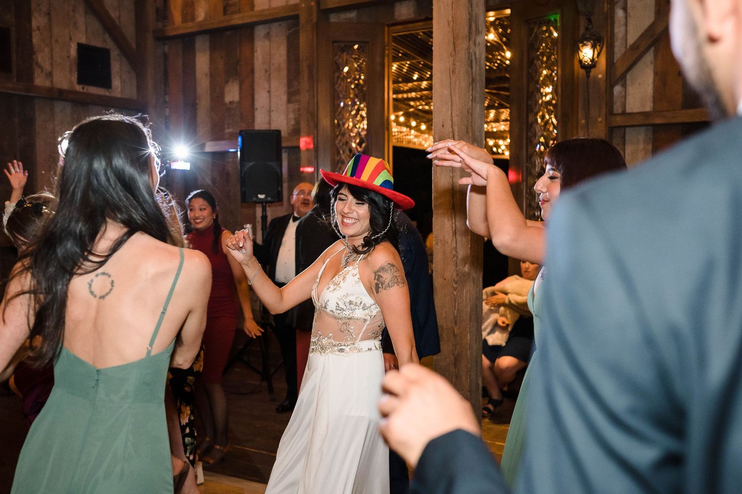 Guests dancing and celebrating at a rustic barn wedding reception with string lights.