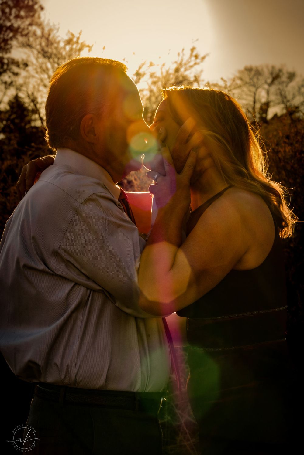 Silhouetted couple shares romantic kiss in Sedona golden sunset light with lens flare.