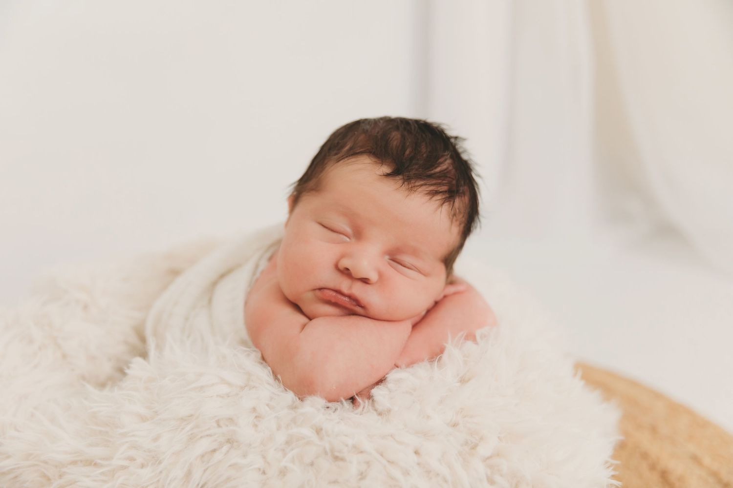 Peaceful sleeping newborn baby wrapped in soft blankets against white background.