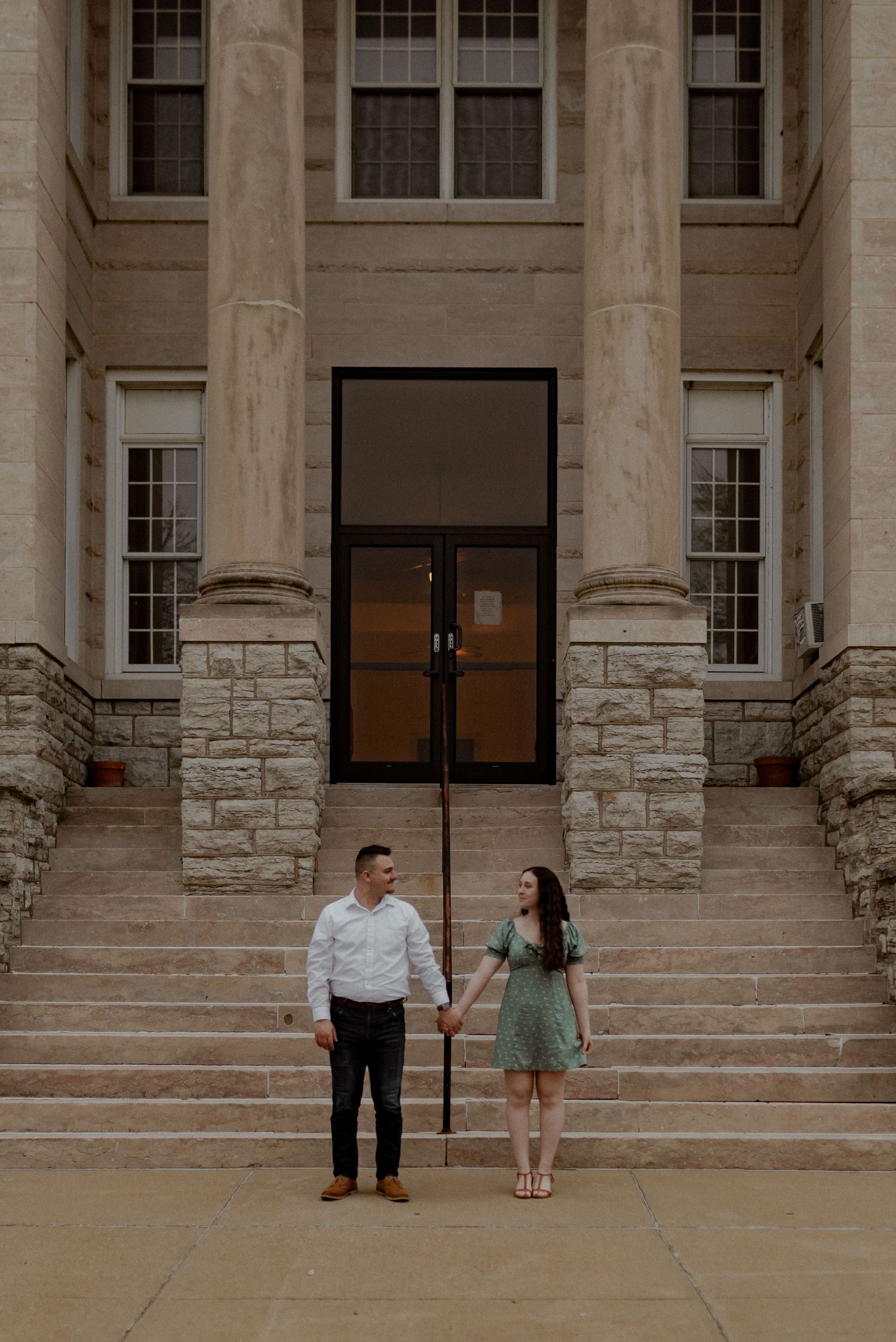 Couple standing together on grand stone steps of historic building.