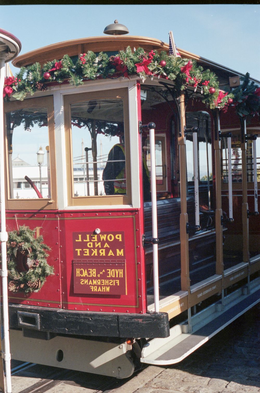 Vintage-style red cable car decorated with holiday garlands and flowers in San Francisco.