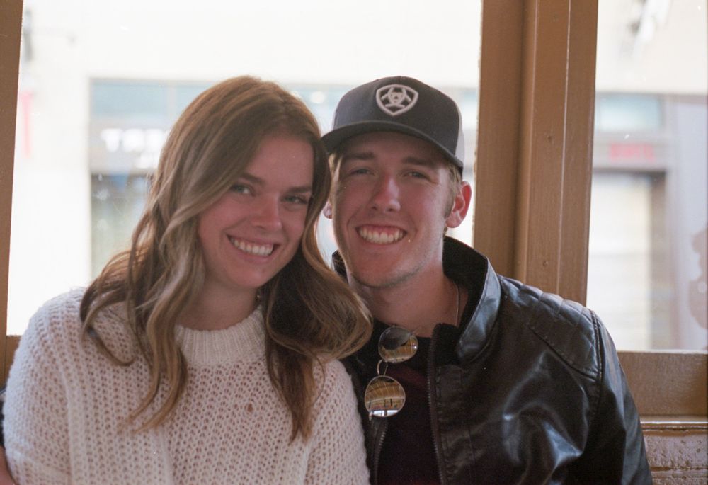 Couple sitting together indoors wearing casual winter clothing.