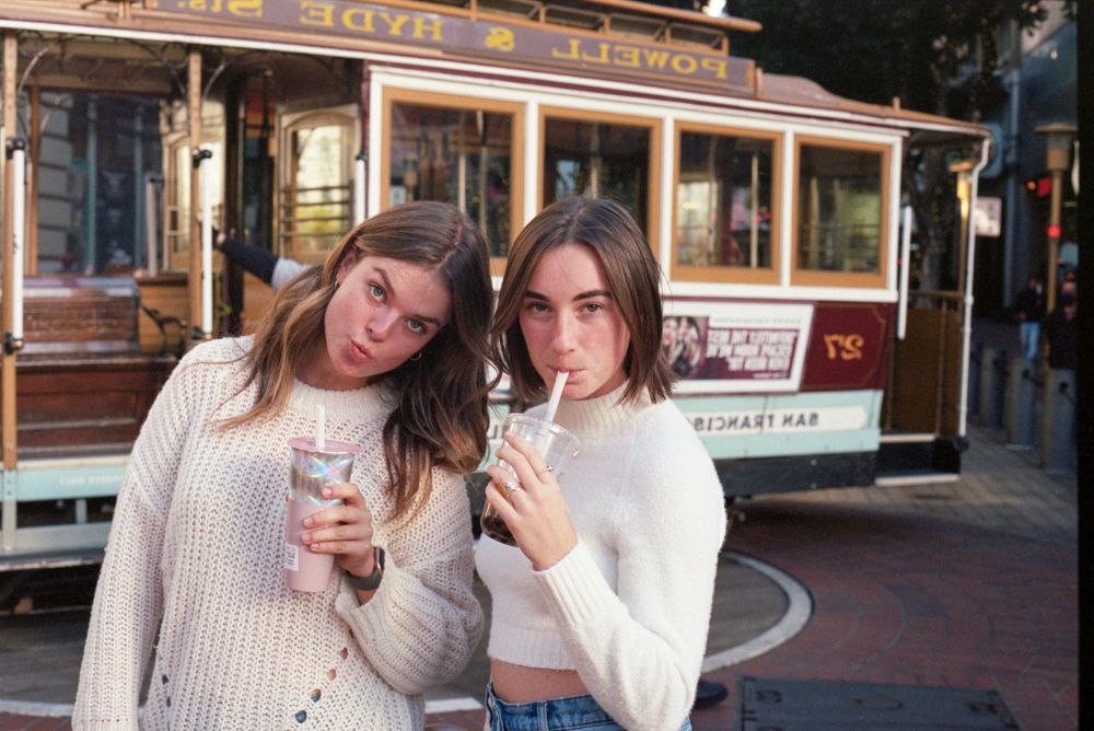 Friends enjoying drinks in front of a historic cable car in San Francisco.