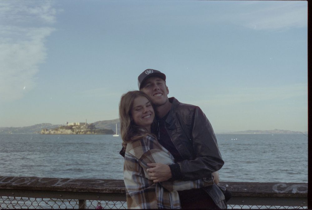 People enjoying the view of Alcatraz Island from a pier in San Francisco Bay.