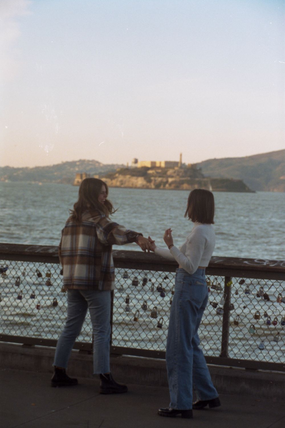 Two people engaged in conversation while enjoying views of Alcatraz Island from the San Francisco waterfront.
