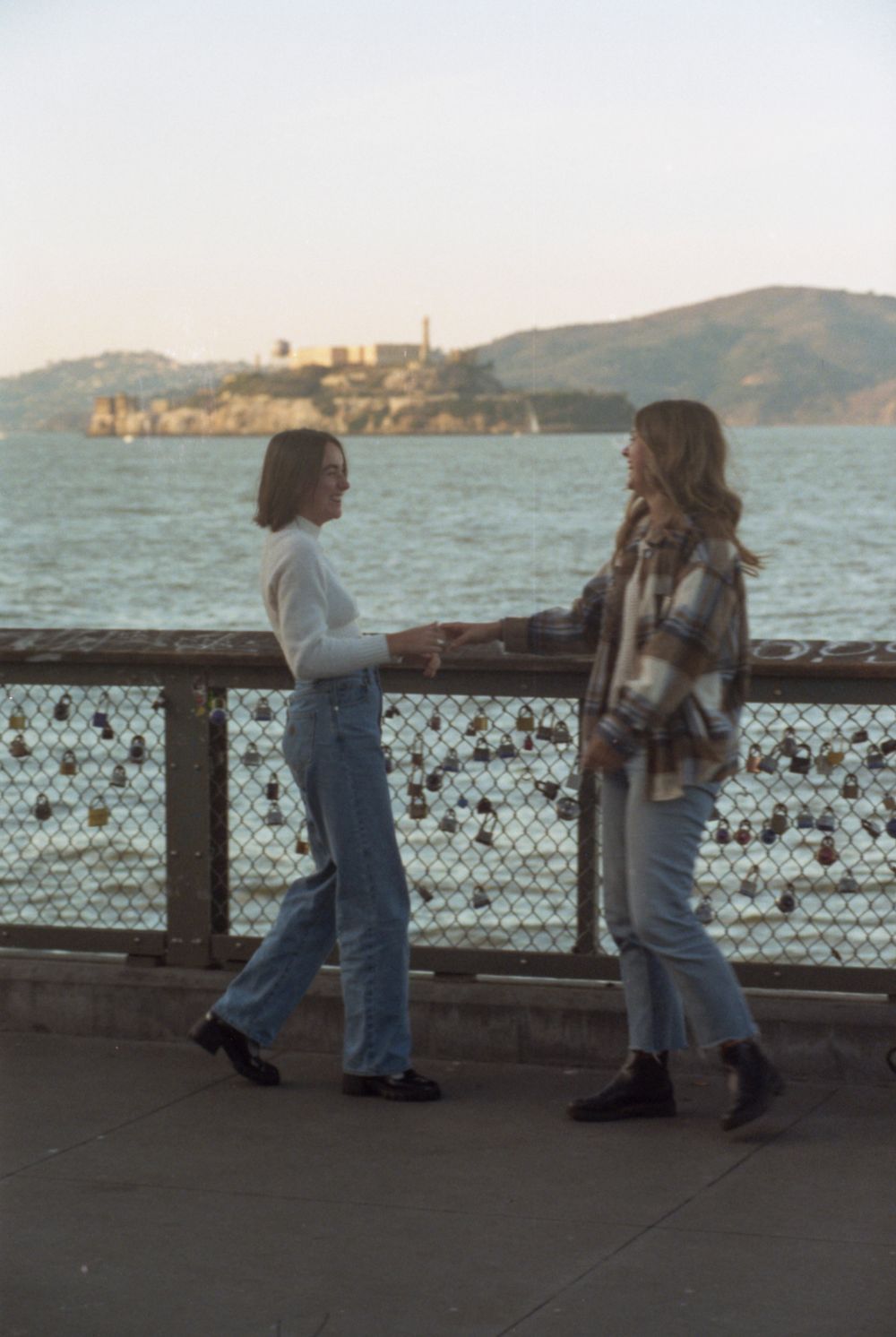 Friends chatting along the San Francisco waterfront with Alcatraz Island visible in the background.