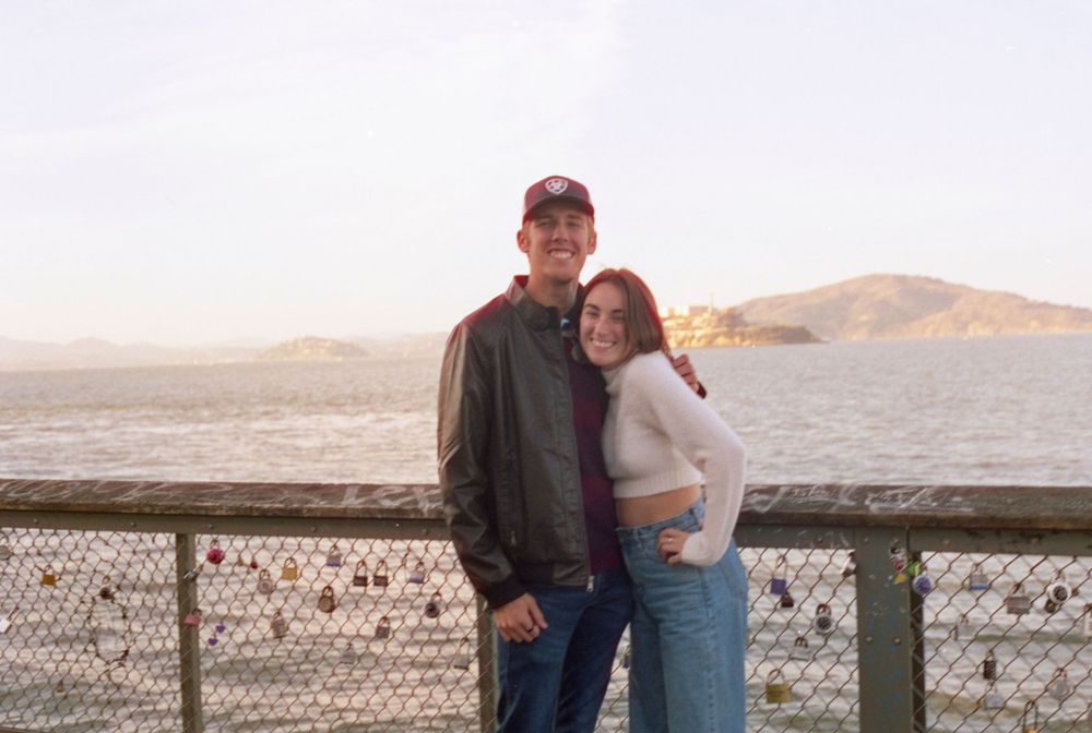 Couple enjoying a sunny day at San Francisco's waterfront with the bay in the background.