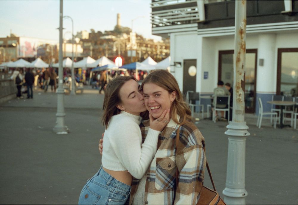 Friends sharing a joyful moment on a busy street in San Francisco's downtown area.