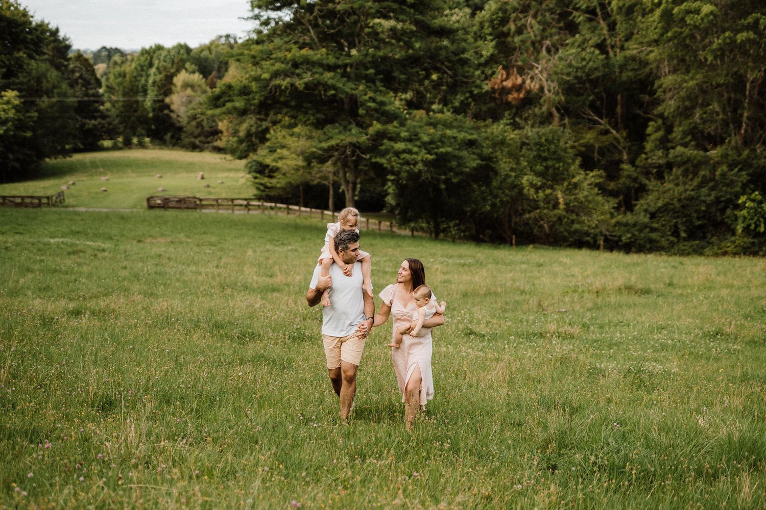 Parent and child walking together through sunny green meadow in summer.