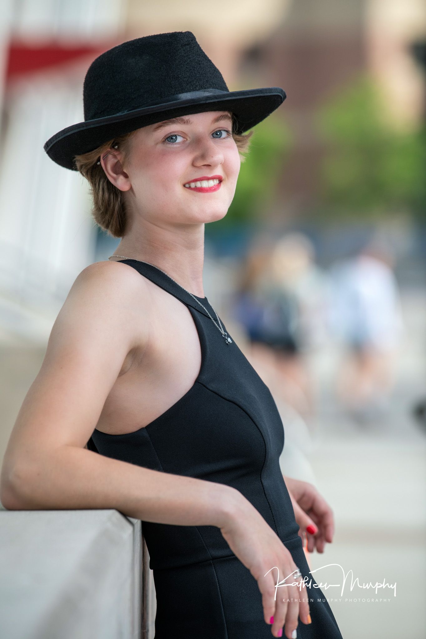 Urban fashion portrait featuring black hat and sleeveless dress in downtown setting.