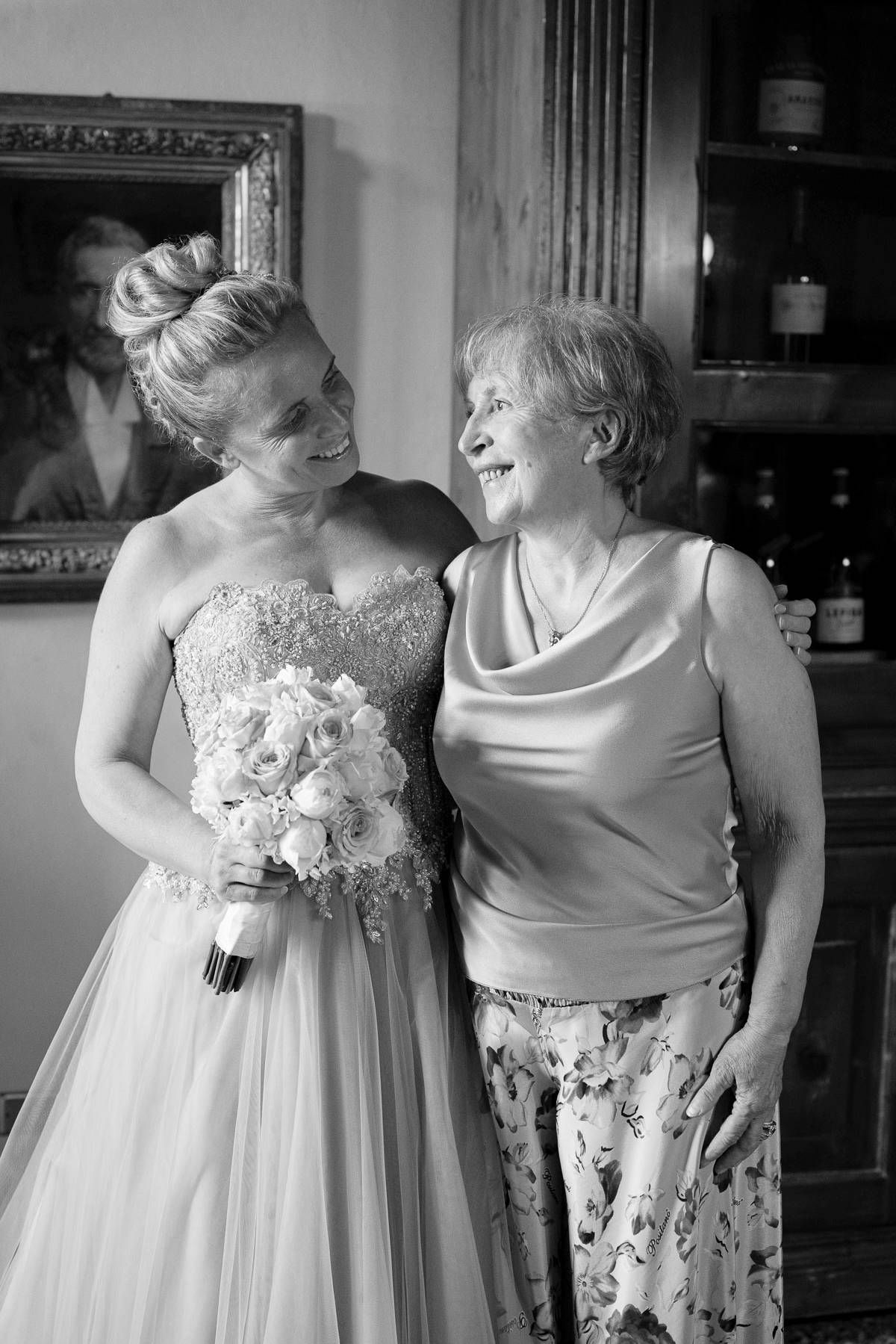 Black and white photo capturing a warm moment between two people at a formal event.
