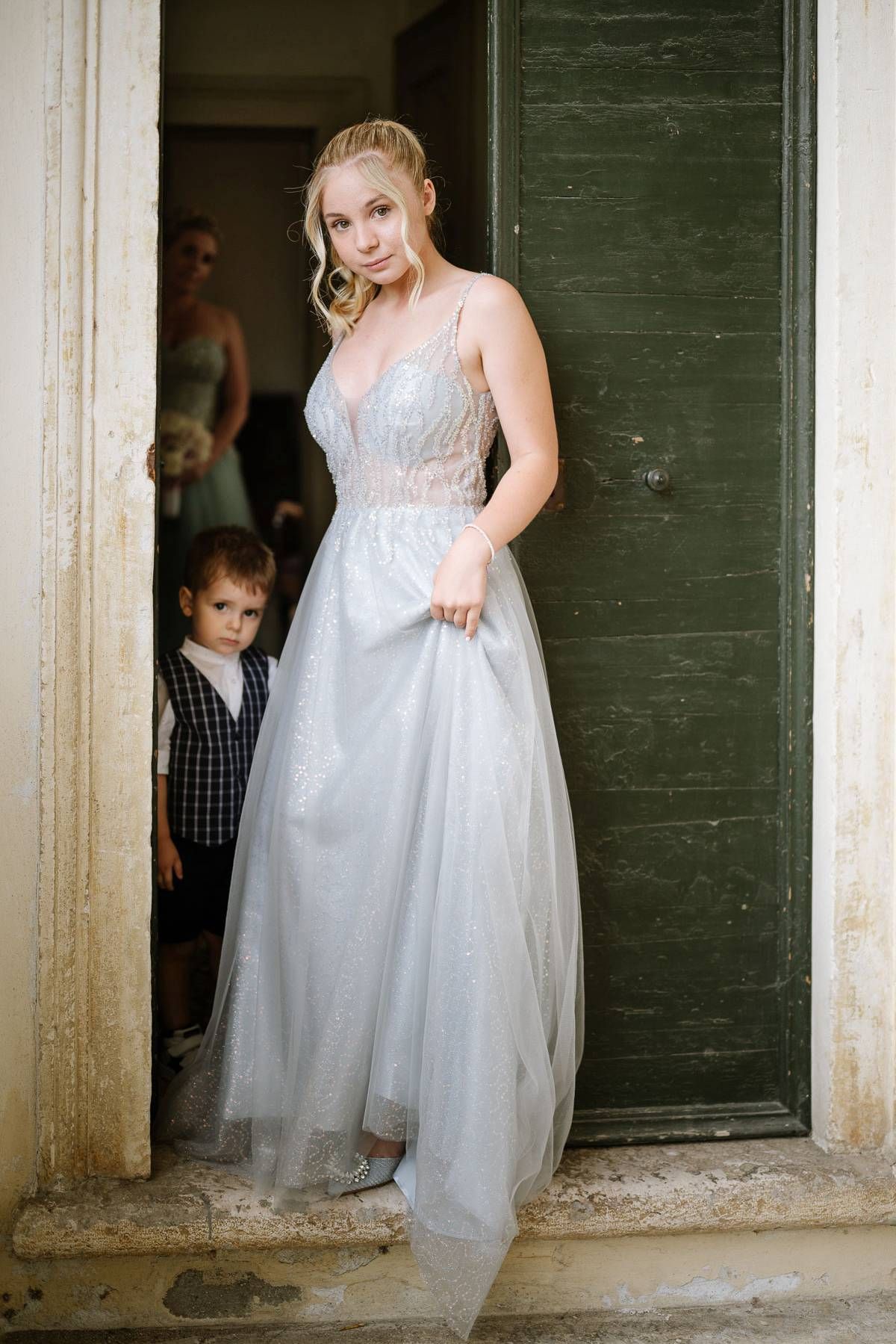 An ethereal light blue wedding gown is showcased in a rustic doorframe setting.
